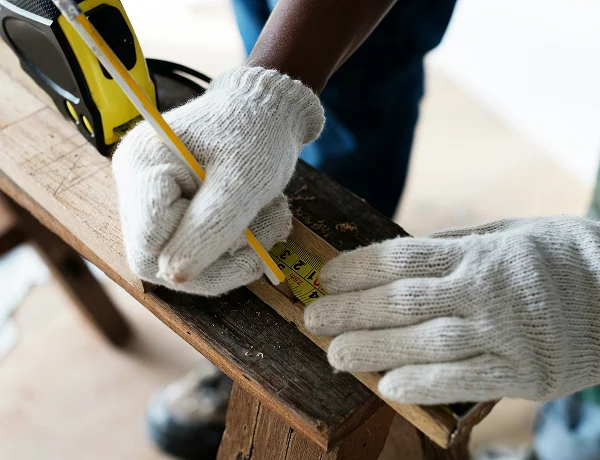 Builder marking out timber with a tape measure