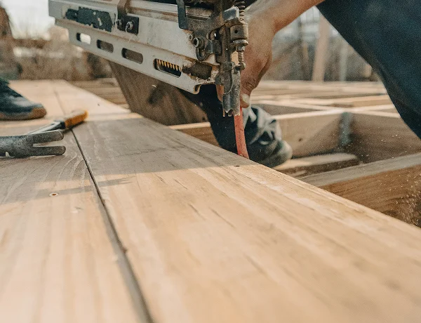 Builder fixing decking boards with a nail gun