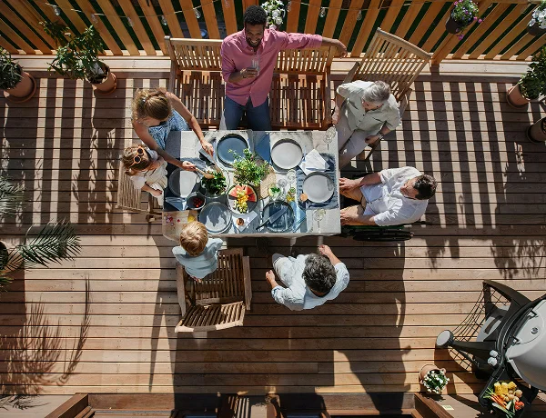 Family sharing a meal at an outdoor table on a timber deck