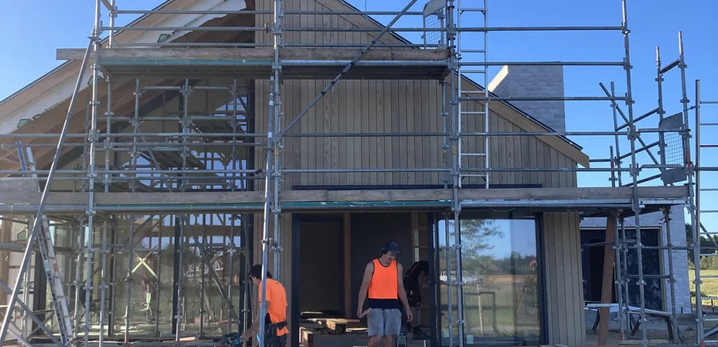 Builders working on a two-storey new build under scaffolding