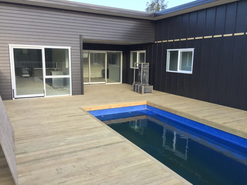 Timber deck wrapping around a swimming pool at a dark-clad home