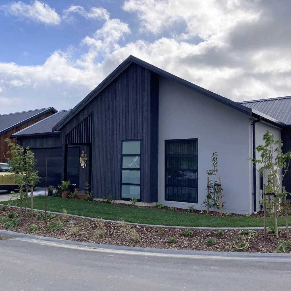 Completed TK Homes new build with dark vertical cladding and landscaped frontage
