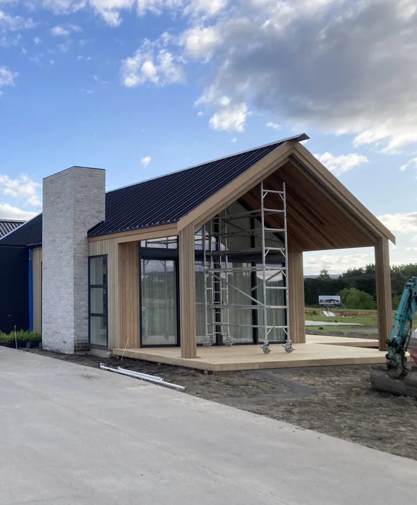 Gable-roofed new build under construction with timber portico and scaffolding